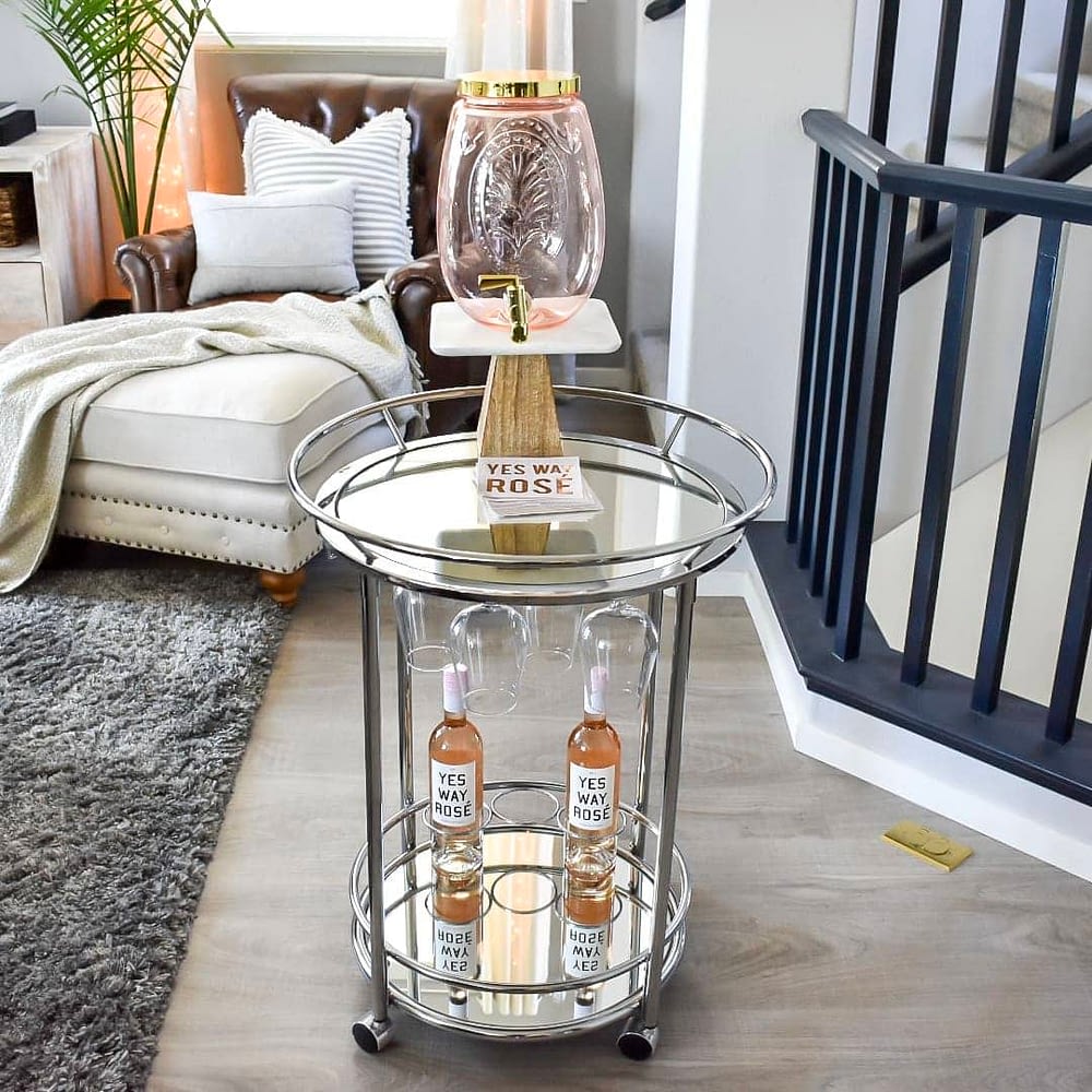 Summer bar cart with empty drink dispenser and hanging wine glasses