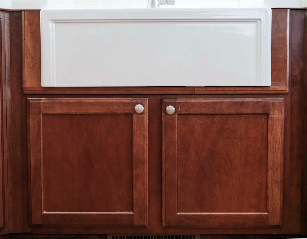 View of white farmhouse sink with custom built cabinet doors below