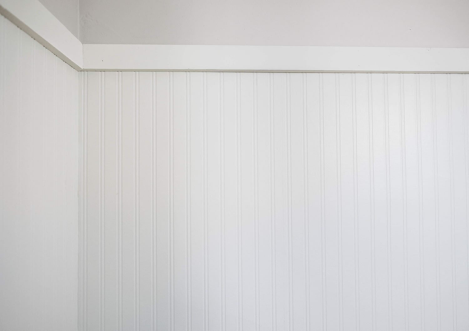 White beadboard wallpaper against light grey wall