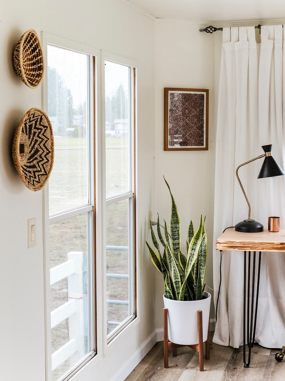 Home office inspiration with woven baskets on the wall and a snake plant in the corner