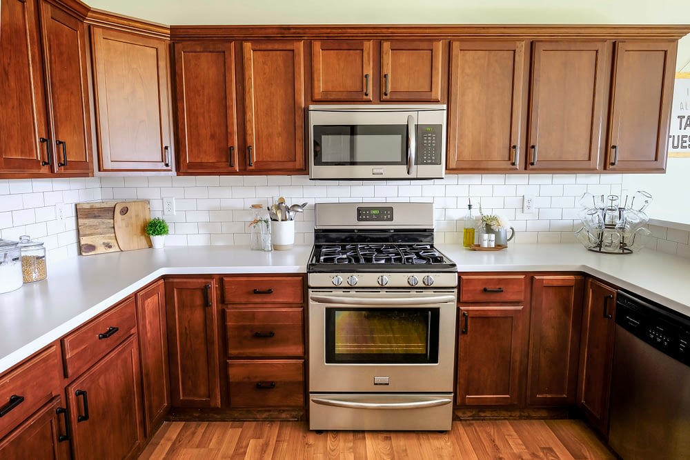 kitchen after remodel with wood cabinets, white countertops and subway tile backslash 