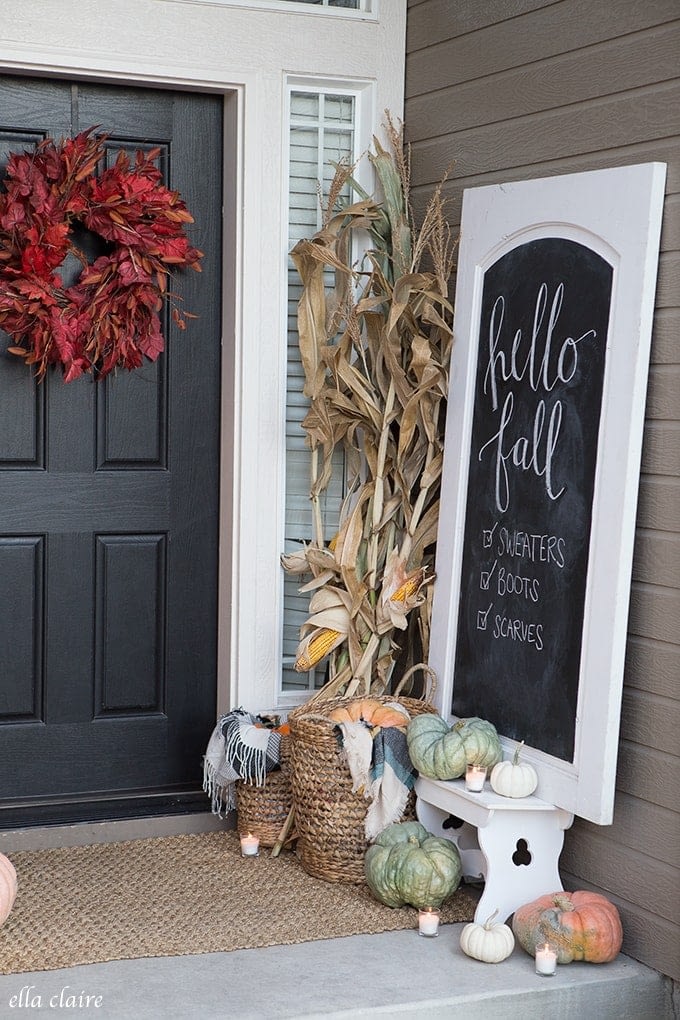 Fall front porch ideas using a red wreath, corn stalks and a chalkboard sign