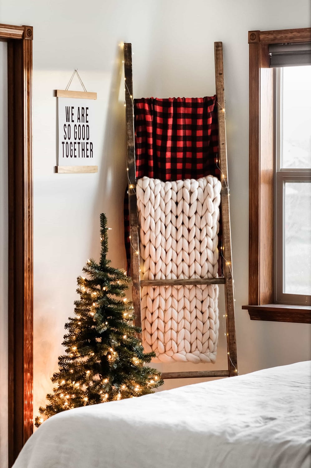 A blanket ladder holding a white woven blanket, and a red buffalo check blanket