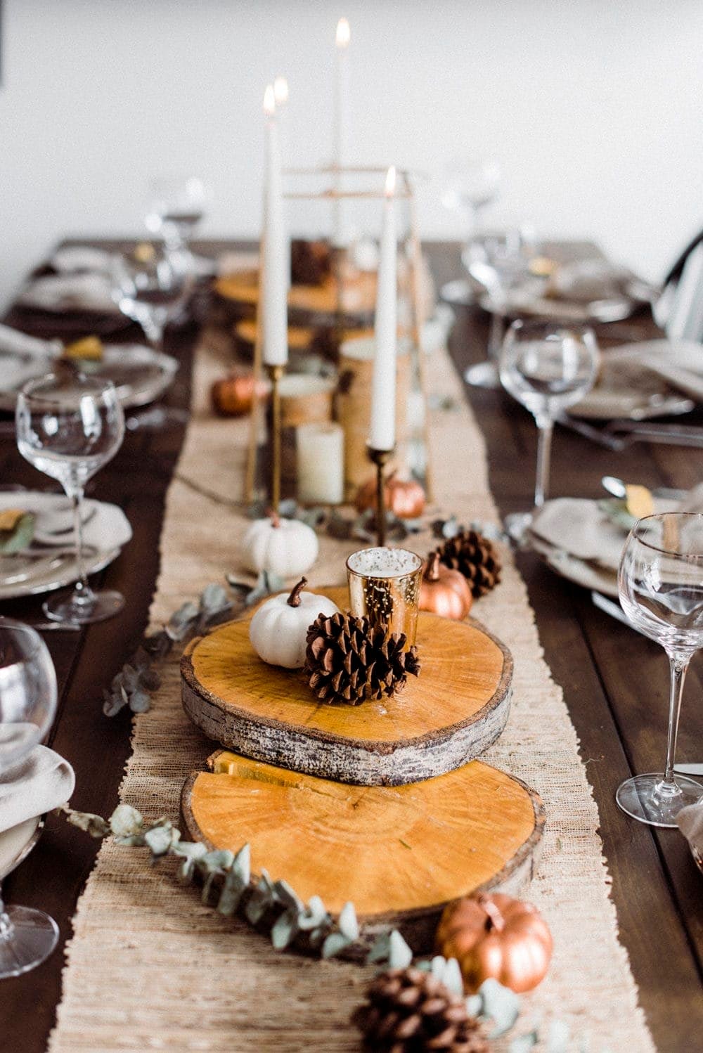 Thanksgiving table centerpieces with a jute table runner, round tree slices and vintage brass candlesticks