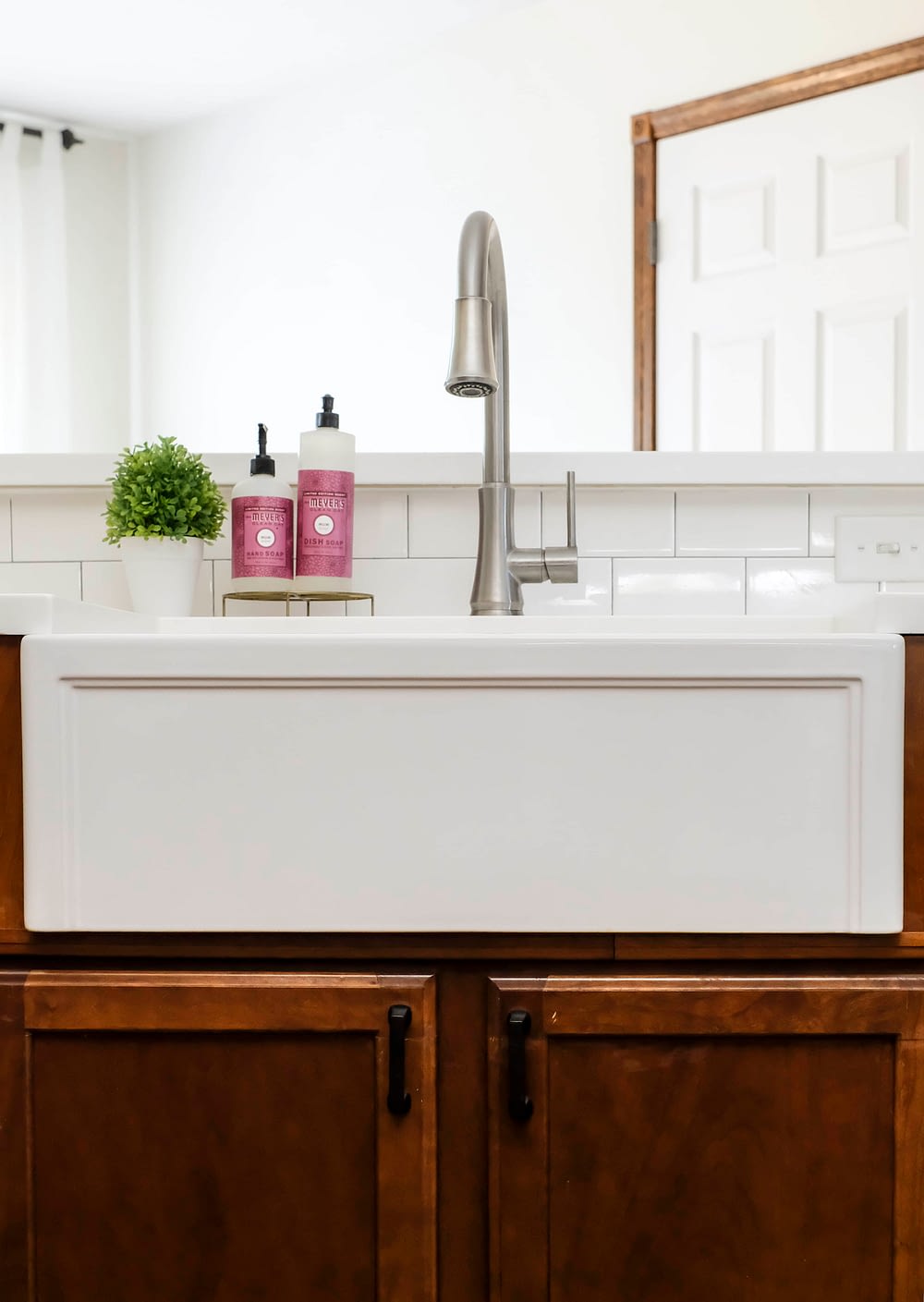 A white apron front fireclay farmhouse sink with a brushed nickel pull down faucet