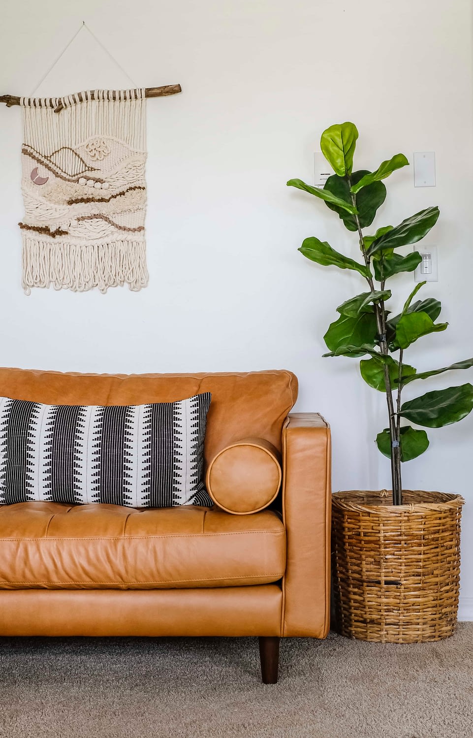 faux fiddle leaf fig tree standing next to a leather couch