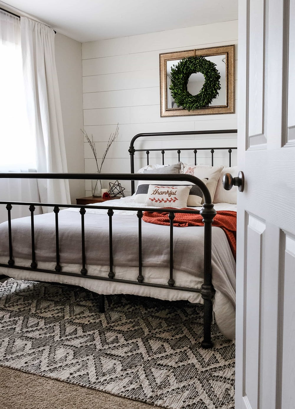 a modern farmhouse bedroom with white shiplap wall