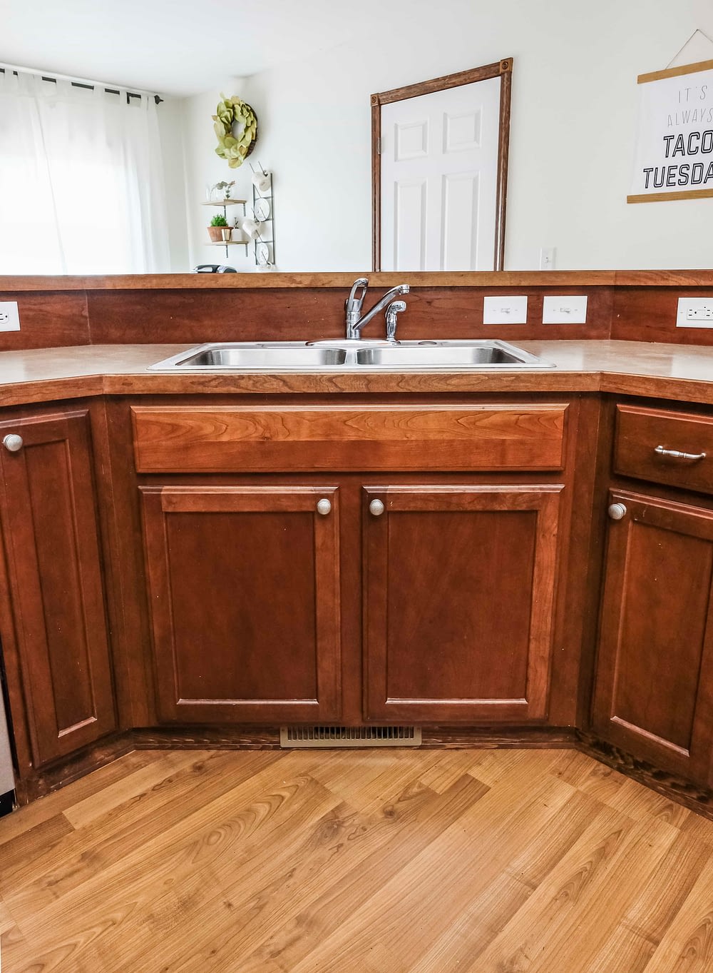 A stainless steel builder grade sink with dark wood cabinets