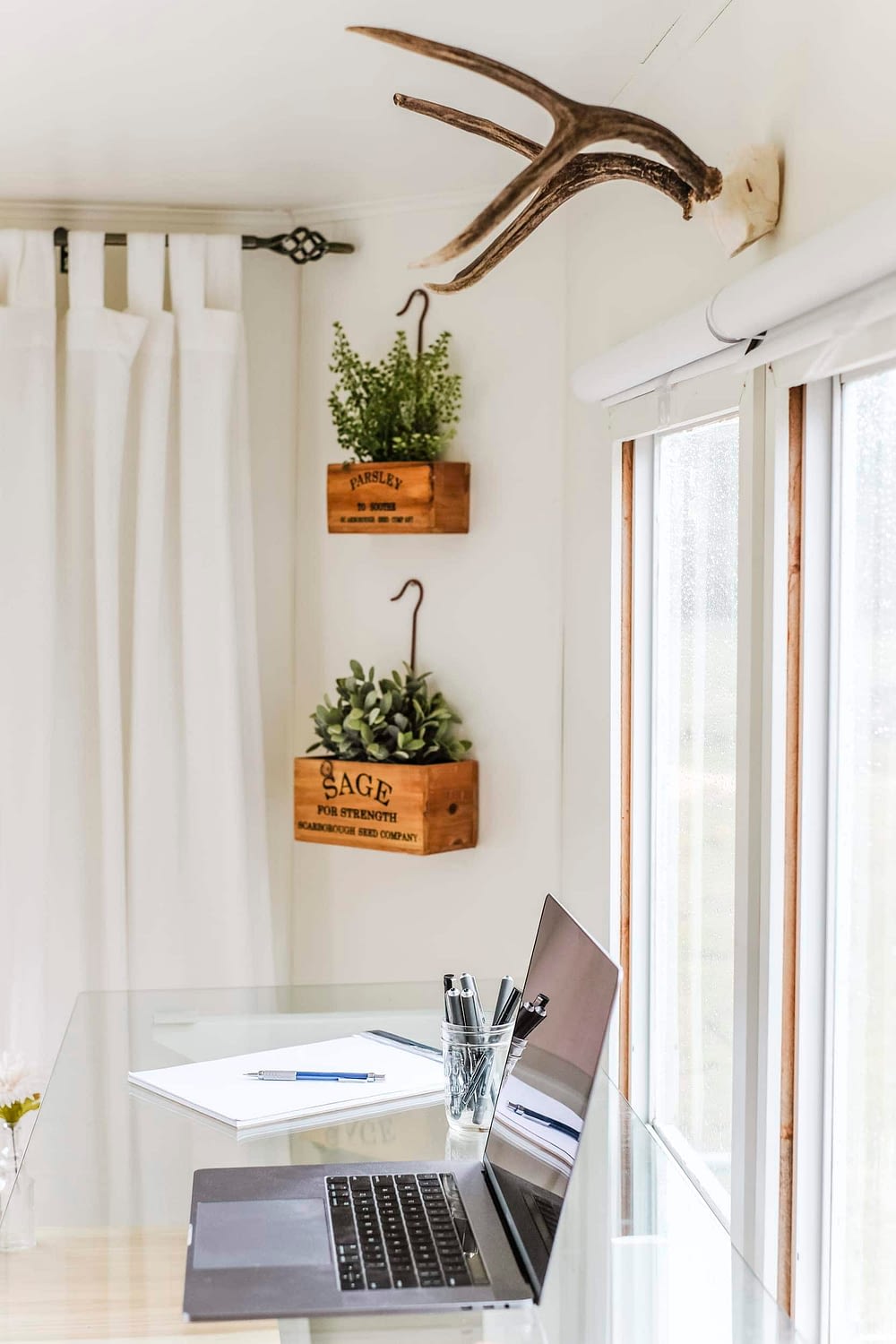 Home office with antlers on the wall and a laptop on a glass desktop