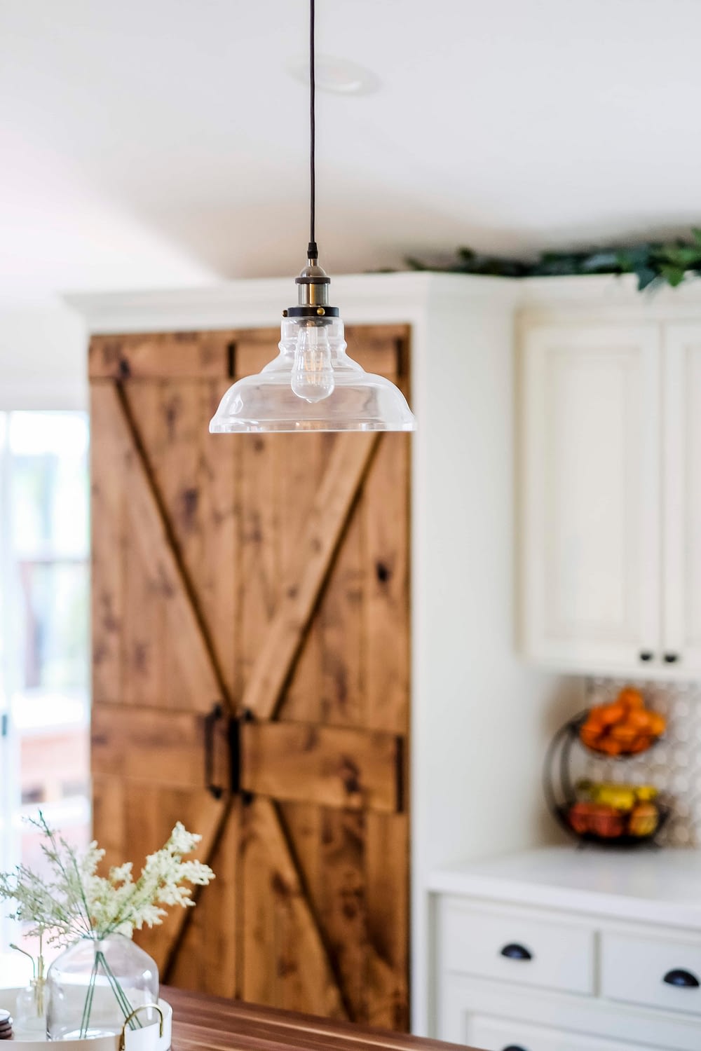 Glass pendant light hanging in white farmhouse kitchen on a budget