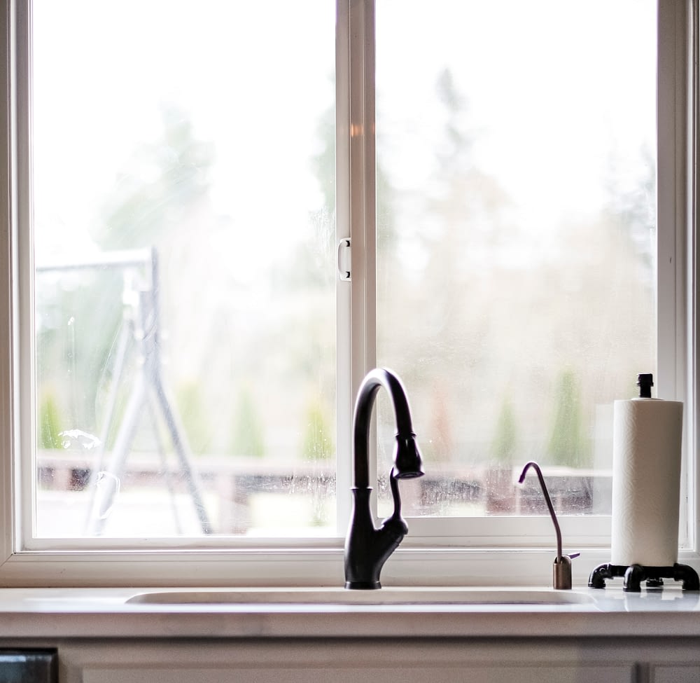 Kitchen sink with oil rubbed faucet in front of a large window