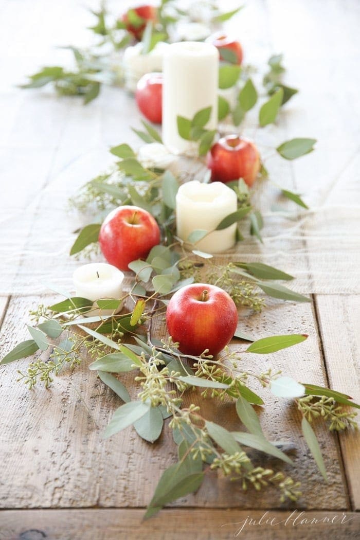 Thanksgiving table centerpieces using eucalyptus runner and apples and candles