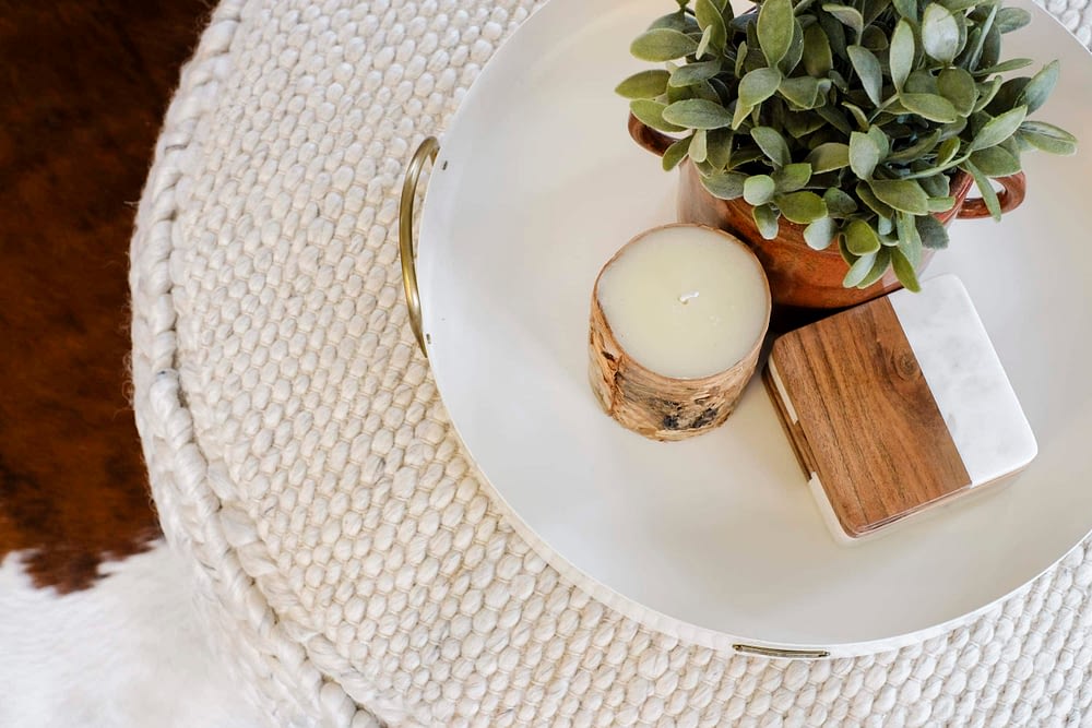 Overhead angle of a decorative tray that has a candle, greenery and coasters 