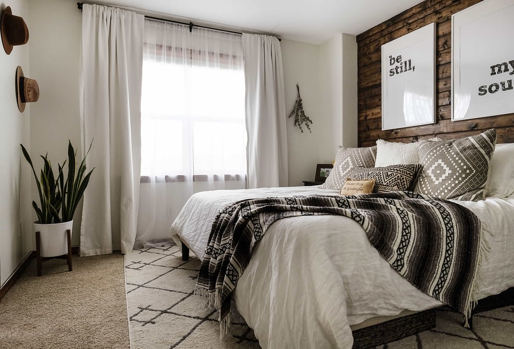 A Decorated bedroom with a walnut stained DIY wood plank accent wall