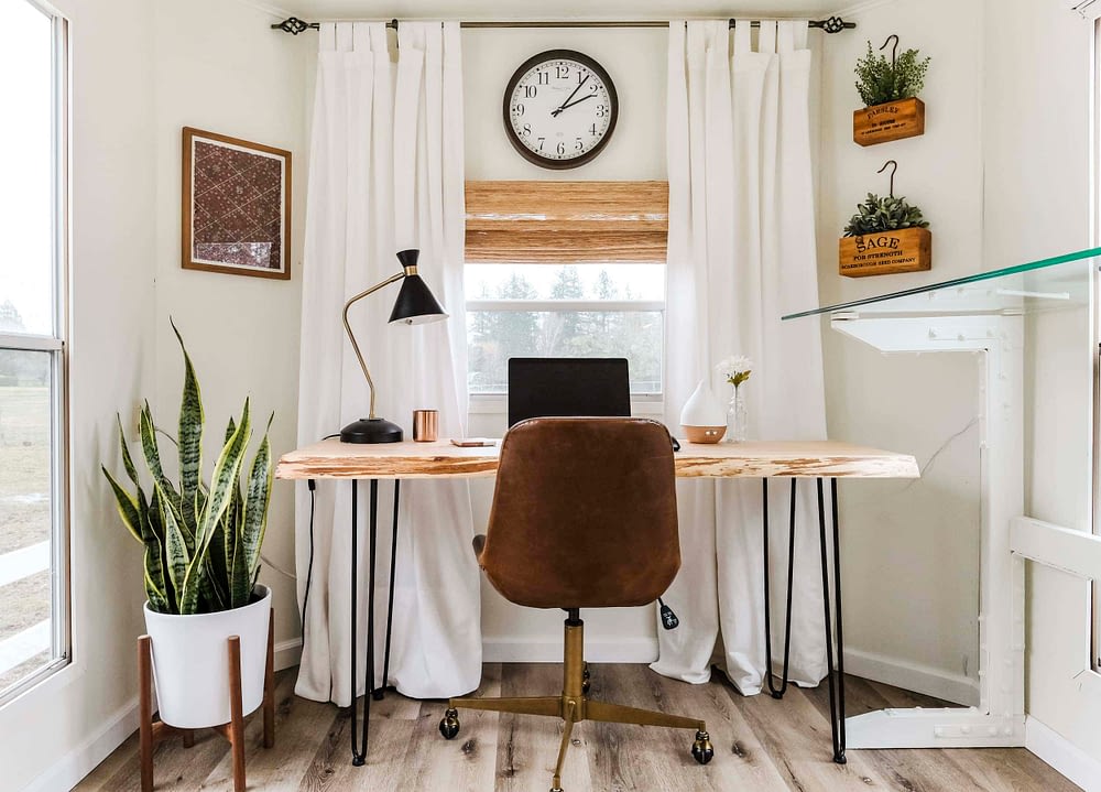 Light and bright home office inspiration with wood desk, snake plant and woven shades