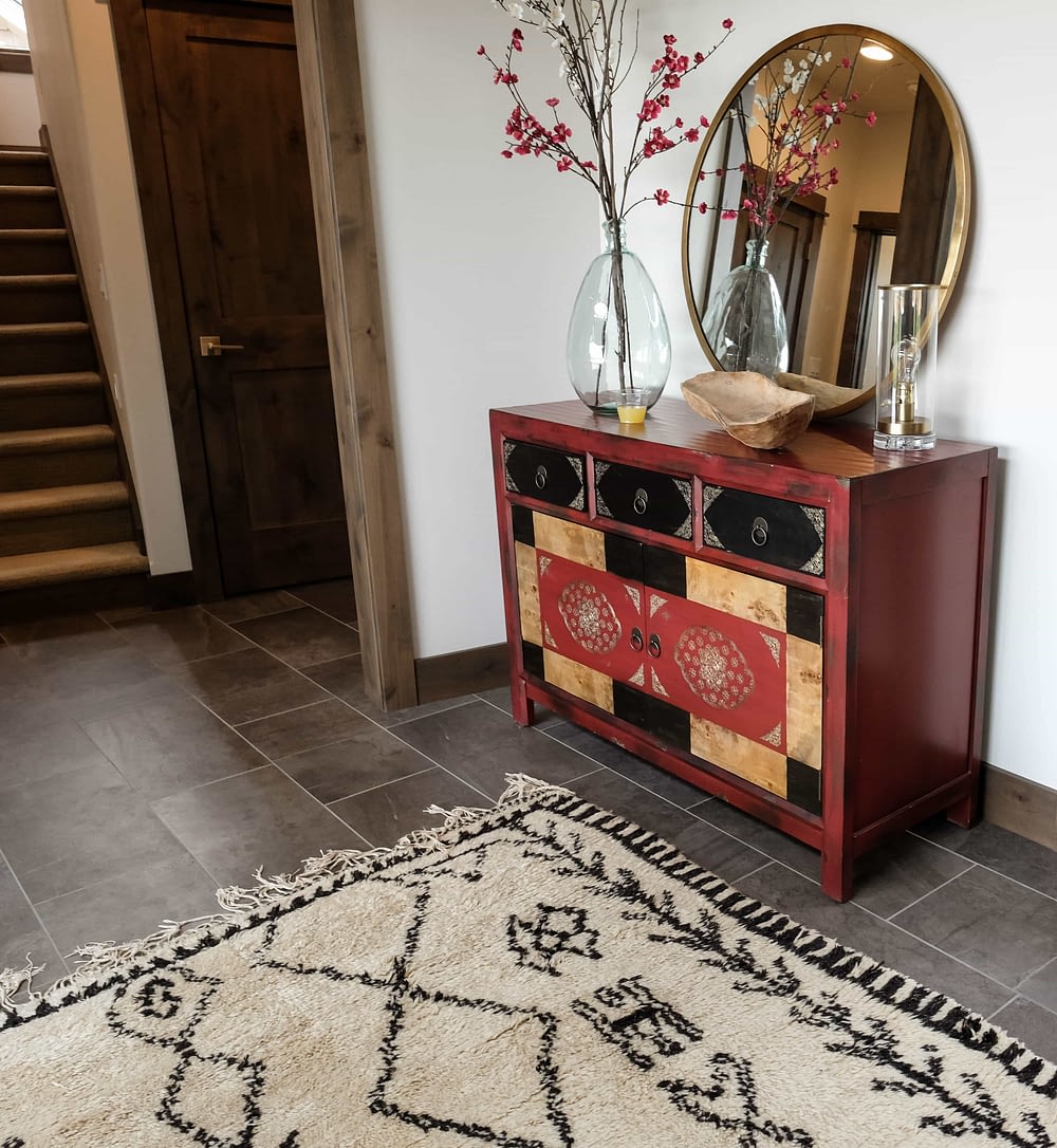 Parade of Homes entryway with grey floor, tan rug, and red dresser