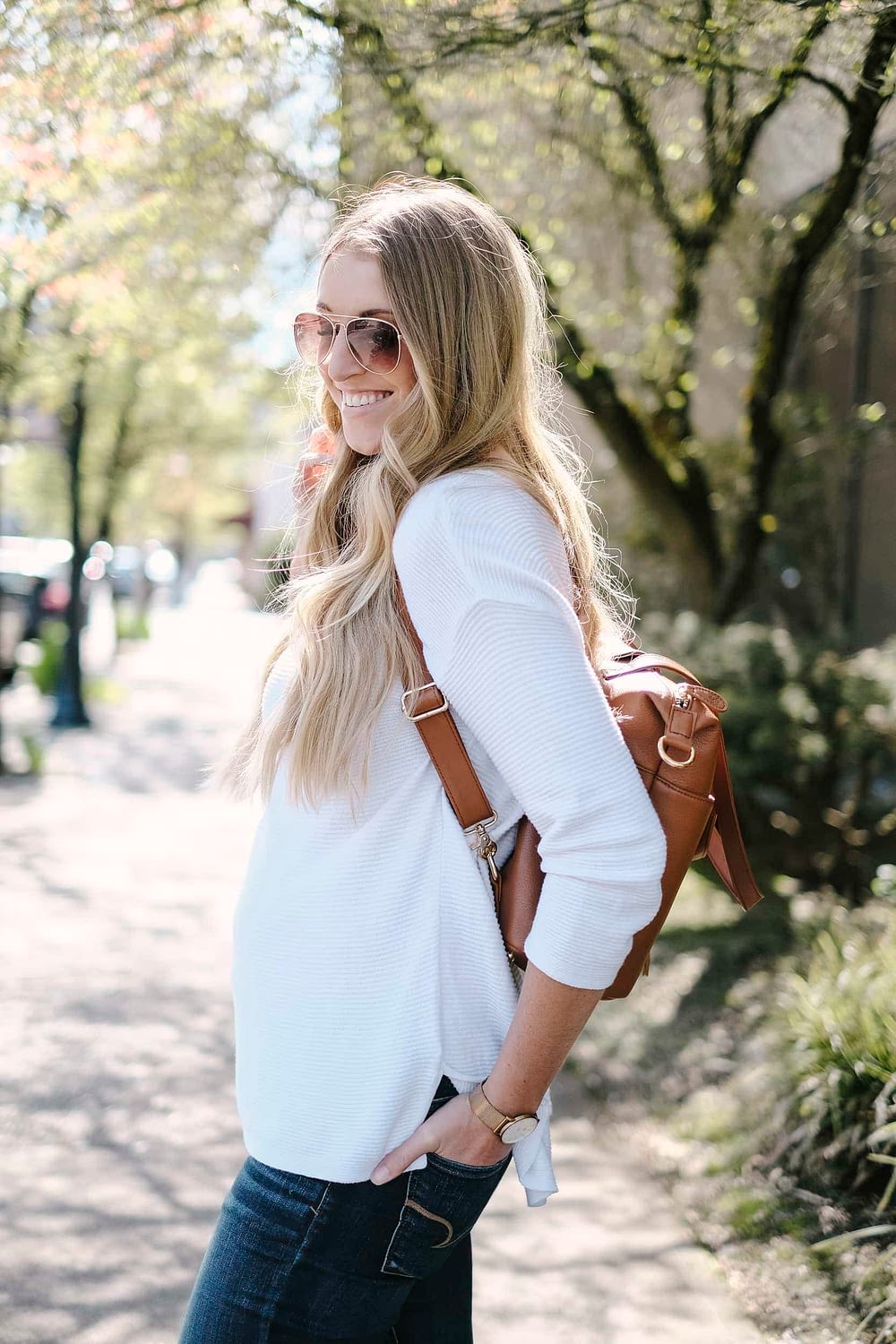 blonde woman with leather diaper bag backpack