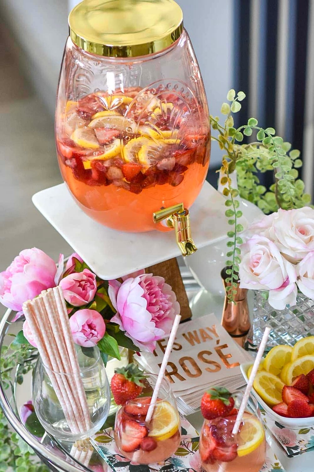 Summer bar cart decorated with flowers and a large drink dispenser with strawberry lemonade sangria