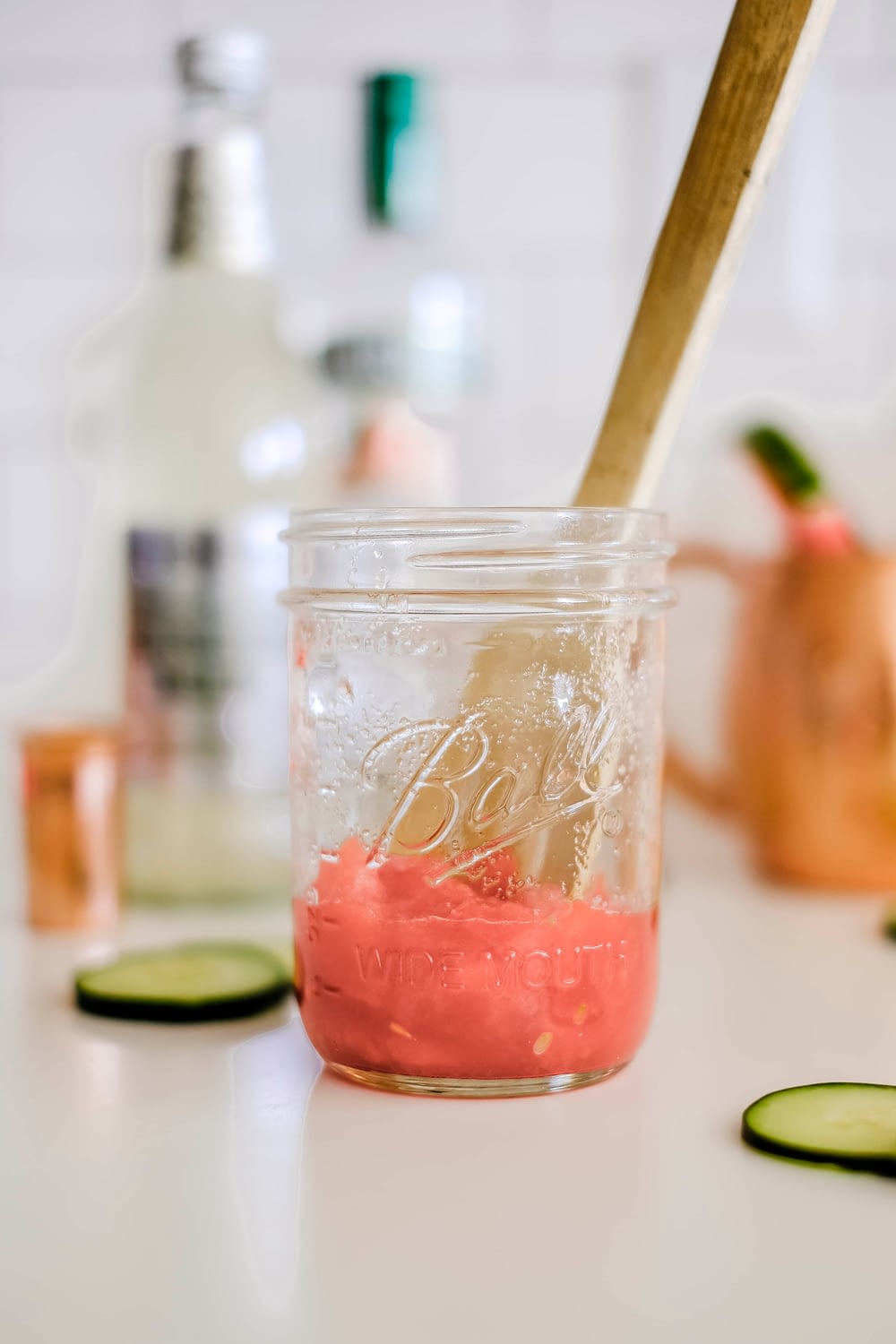 Mason jar with muddled watermelon to use in a cucumber watermelon moscow mule recipe