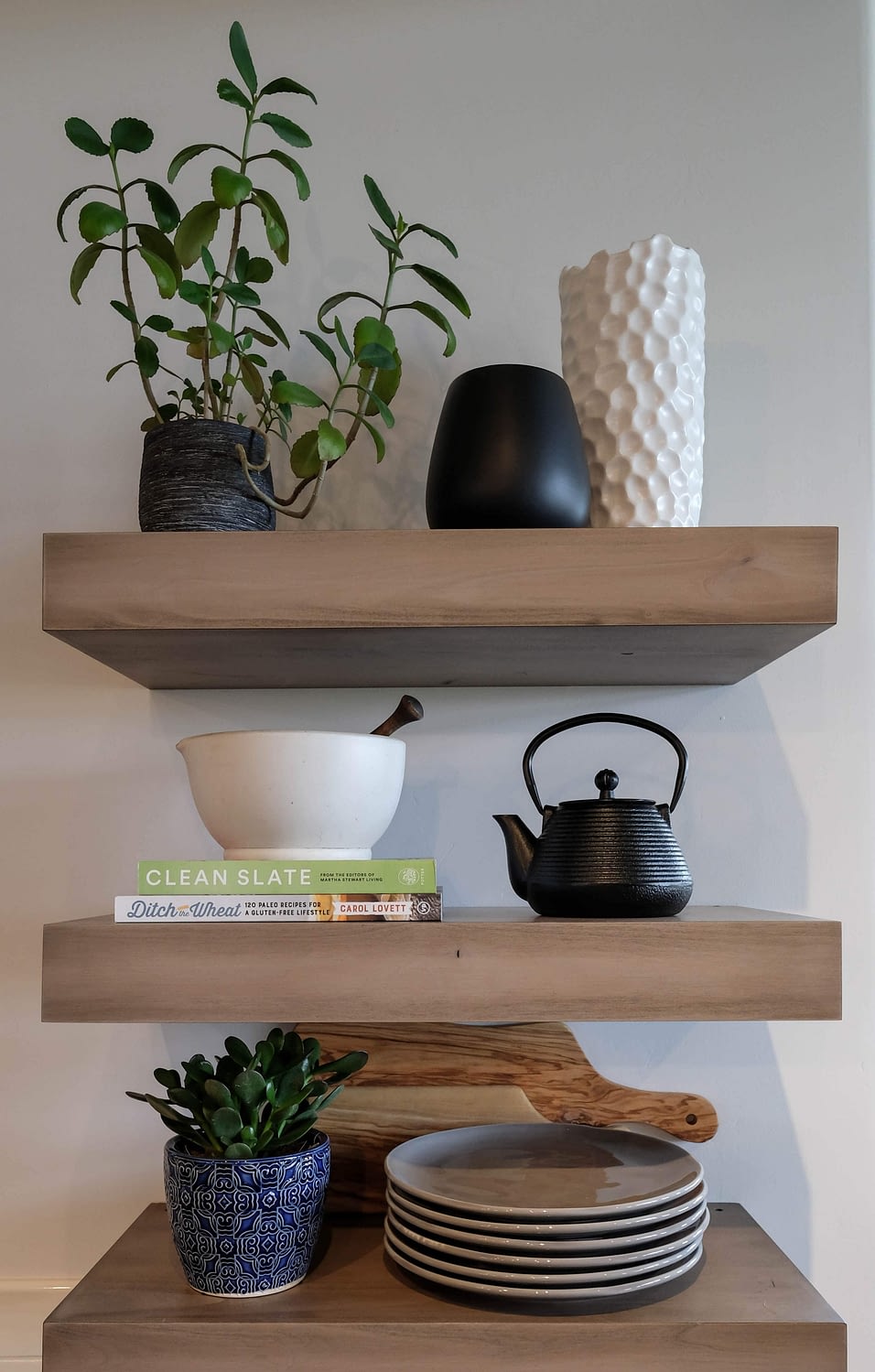 Parade of Homes styled shelf with books, plates, teapot, and plants