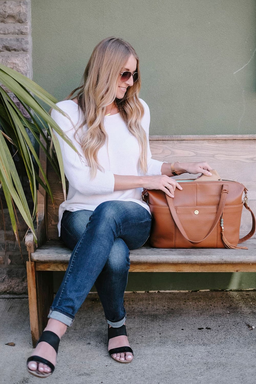 Blonde woman sitting next to lily jade diaper bag on a bench