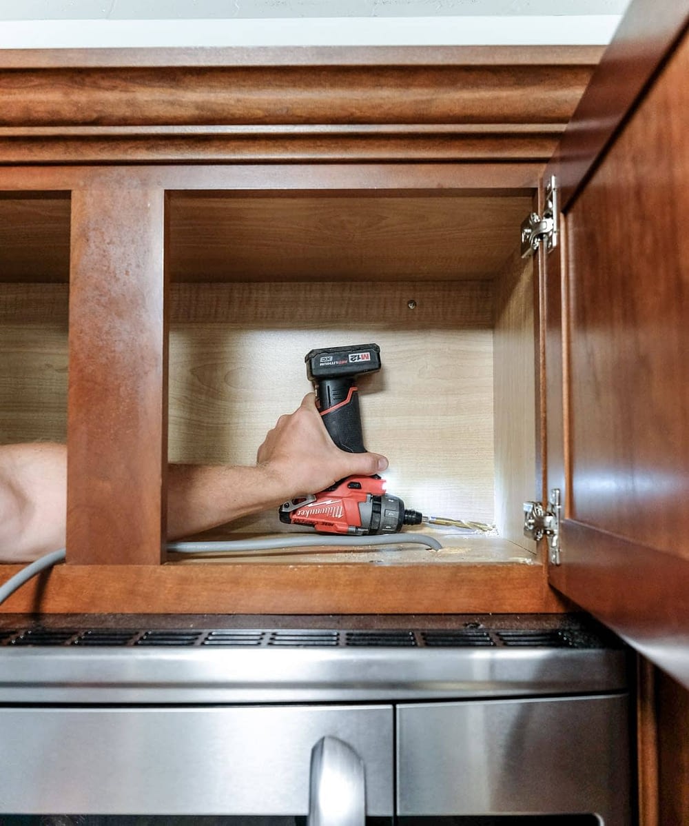 drilling a hole in a kitchen cabinet to add under cabinet lighting