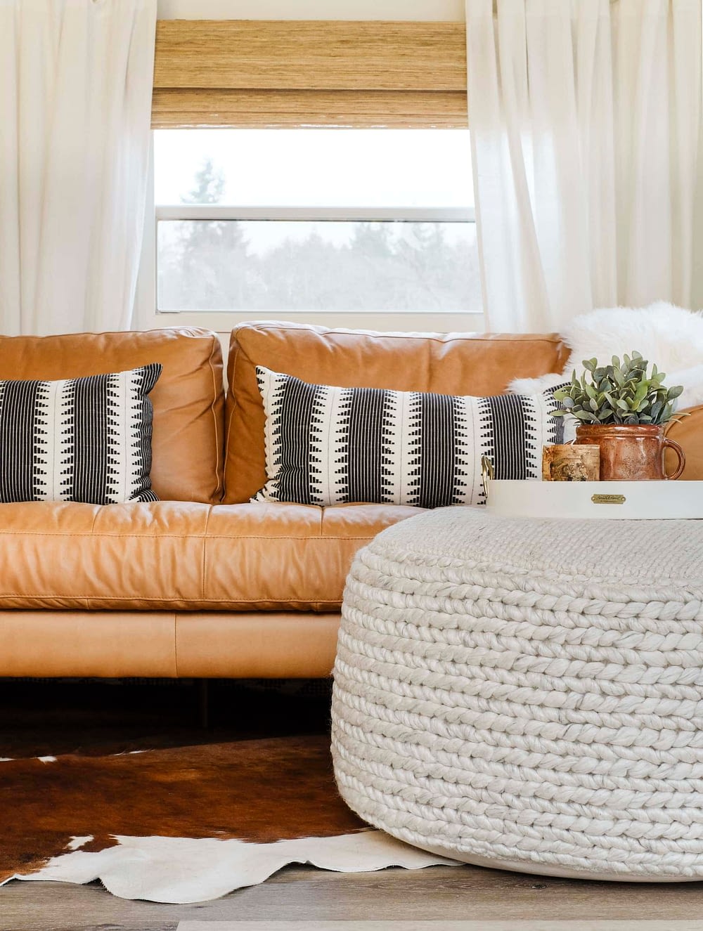 Floor pouf for living room in front of a leather sofa with a decorative tray on top