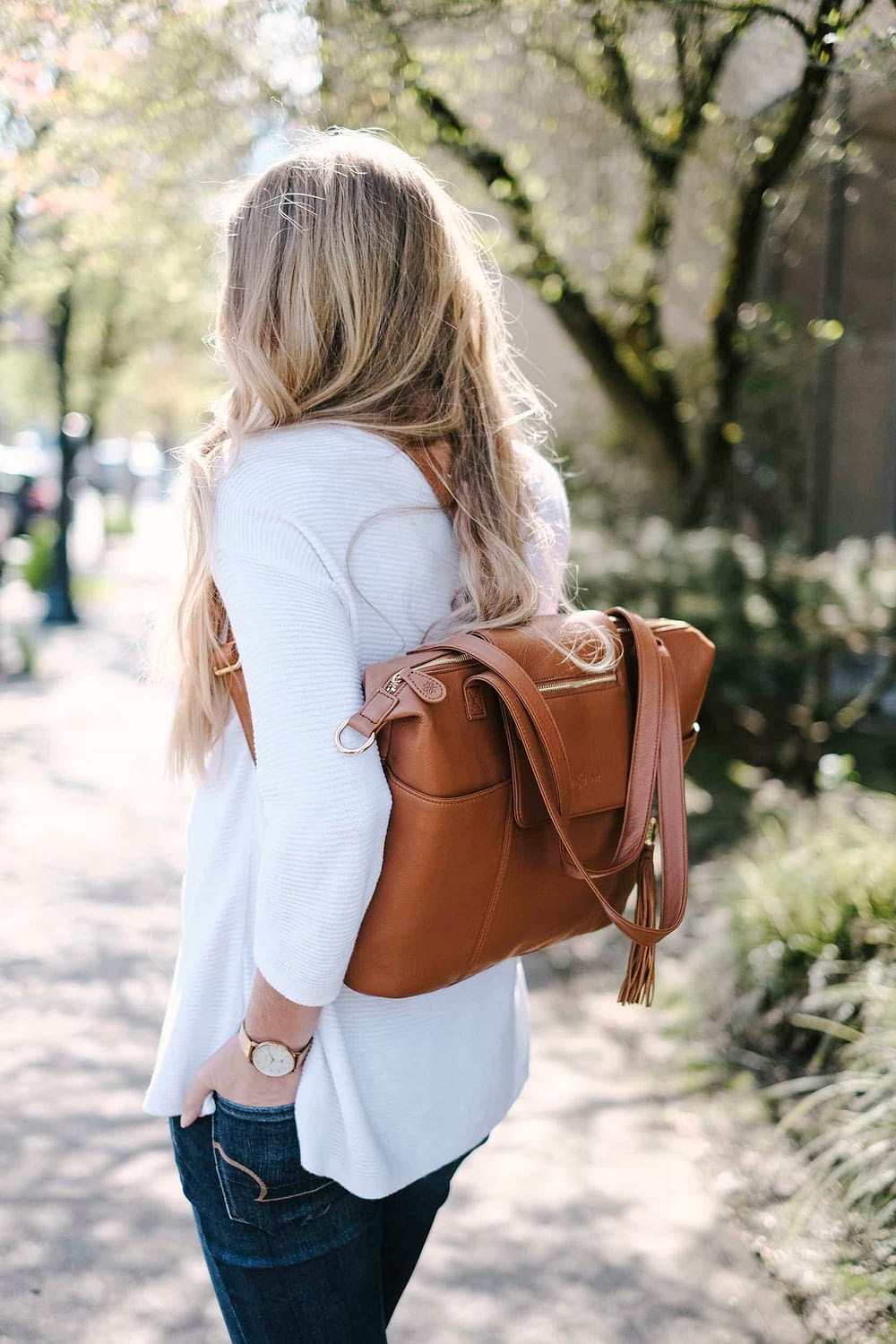 blonde woman with leather diaper bag backpack
