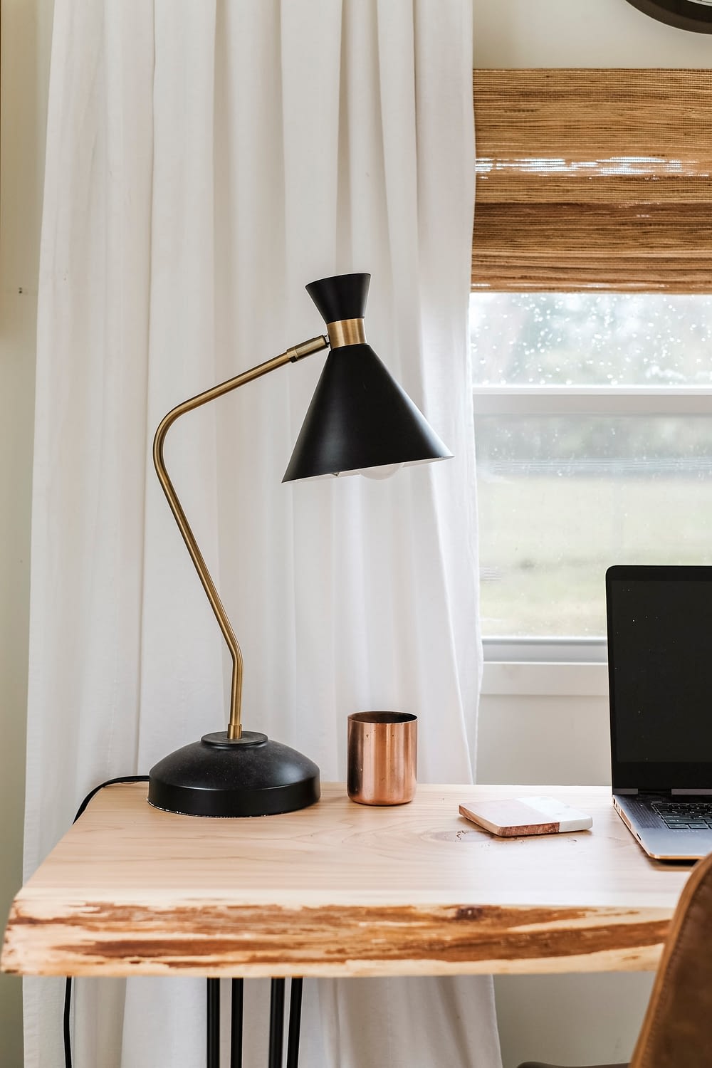 Black modern desk lamp and copper candle on top of wood desk