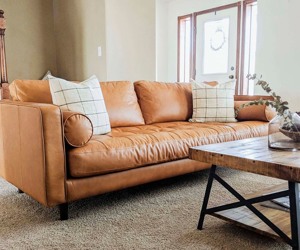 Tan leather sofa with two throw pillows in a living room
