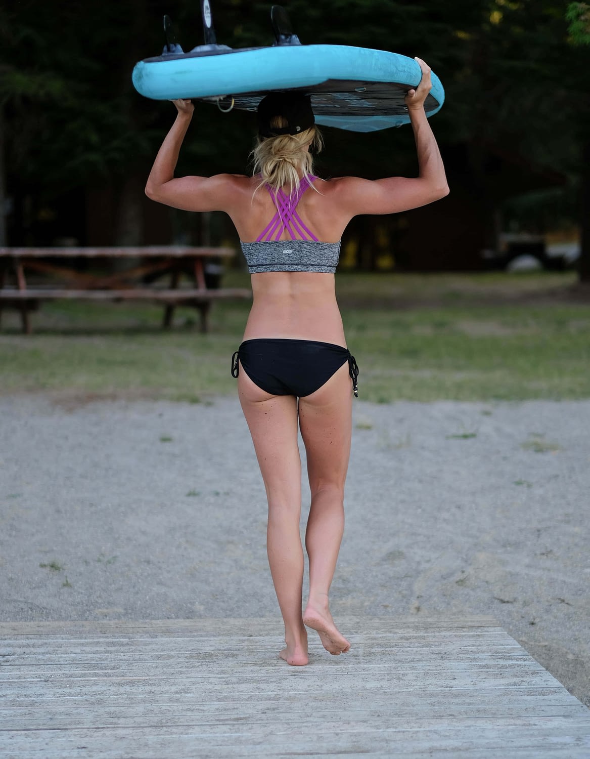 girl carrying an inflatable SUP on her head walking towards the beach