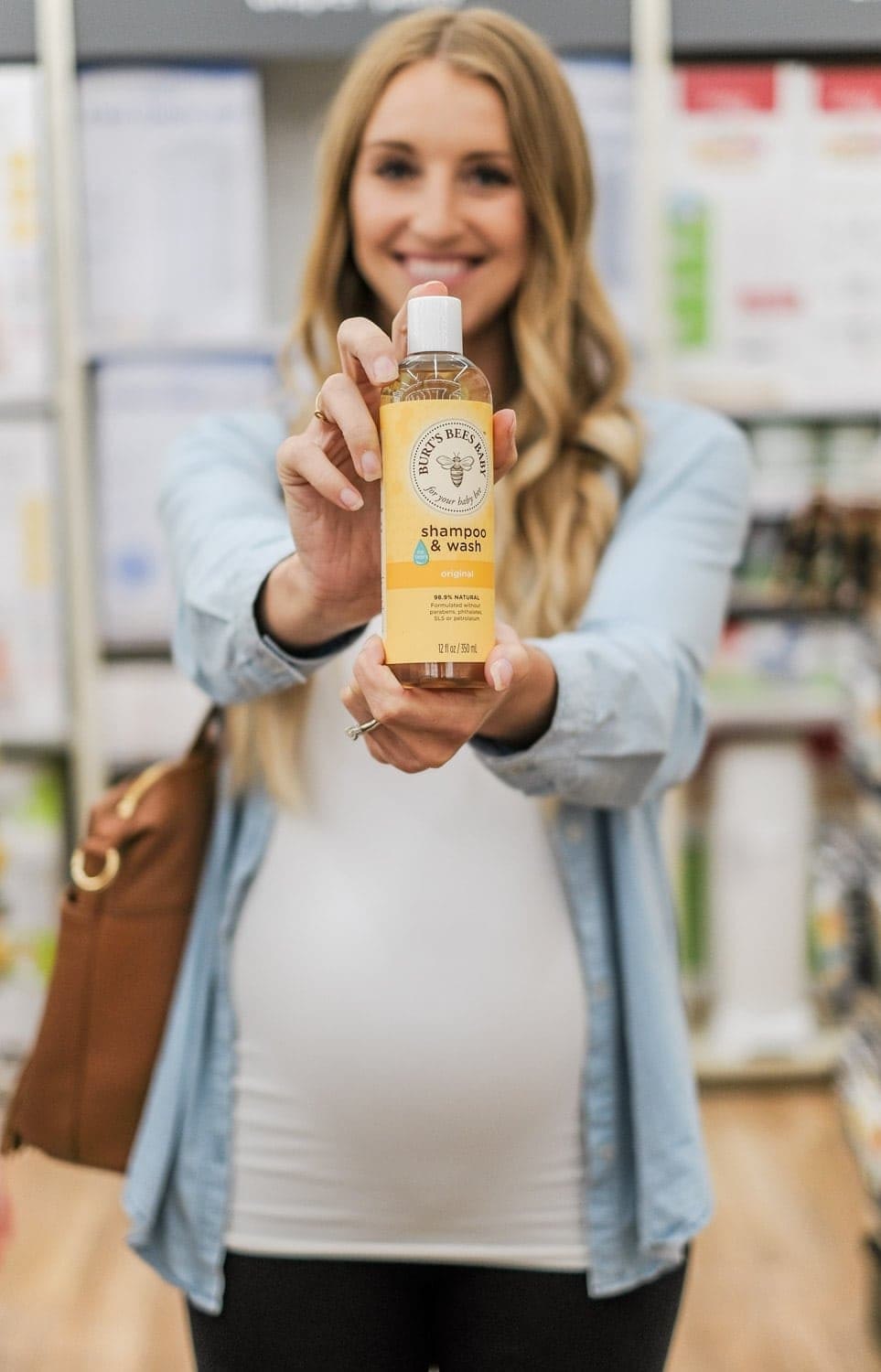pregnant woman holding baby shampoo in buy buy baby store