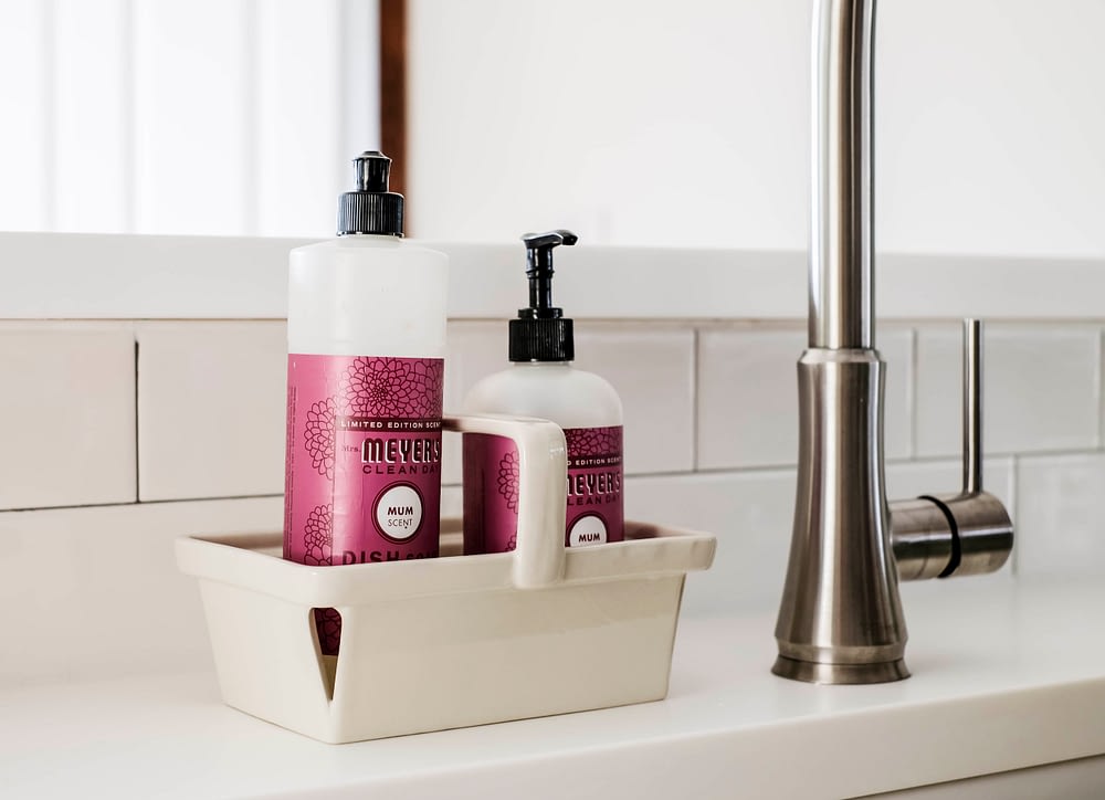 Meyers soap sitting on white solid surface counter tops in front of a subway tile backsplash