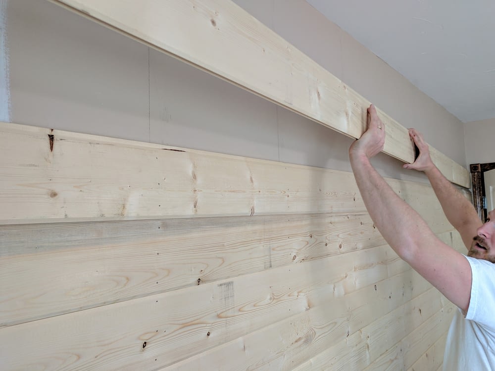 A Man Installing A Board For A DIY Wood Plank Accent Wall