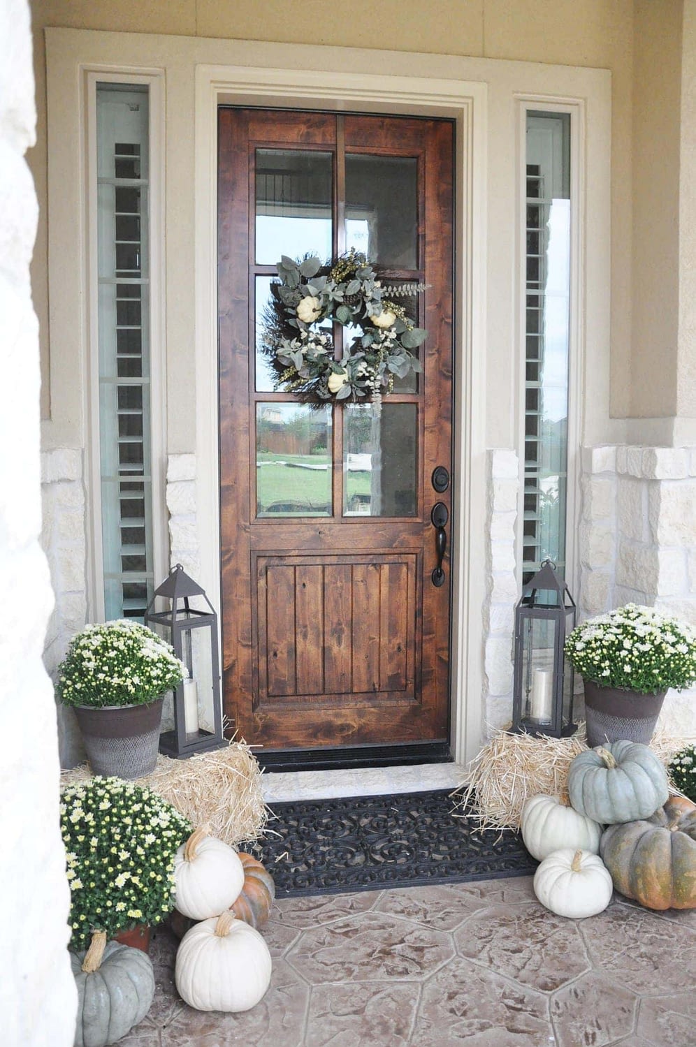 Fall front porch ideas using hay bales, lanterns and neutral colored pumpkins