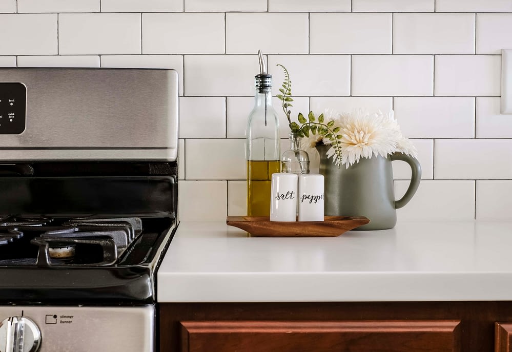 white countertops and subway tile decorated with salt and pepper shakers and olive oil dispenser 