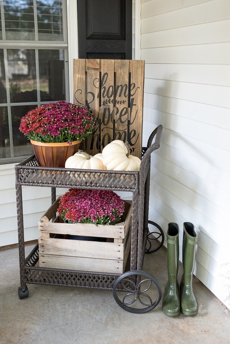 Fall front porch ideas using a tiered cart and wood crates paired with mums and pumpkins
