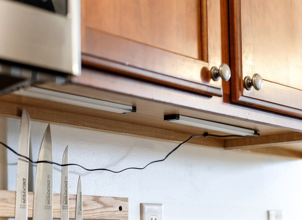 fastening an under cabinet light to the bottom of a kitchen cabinet