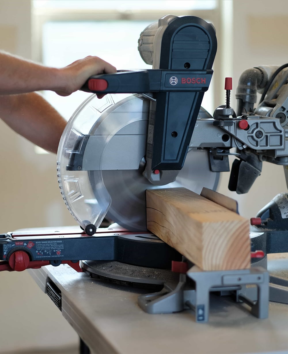 Man using a Bosch Table saw to cut a wood board for a rustic coffee table