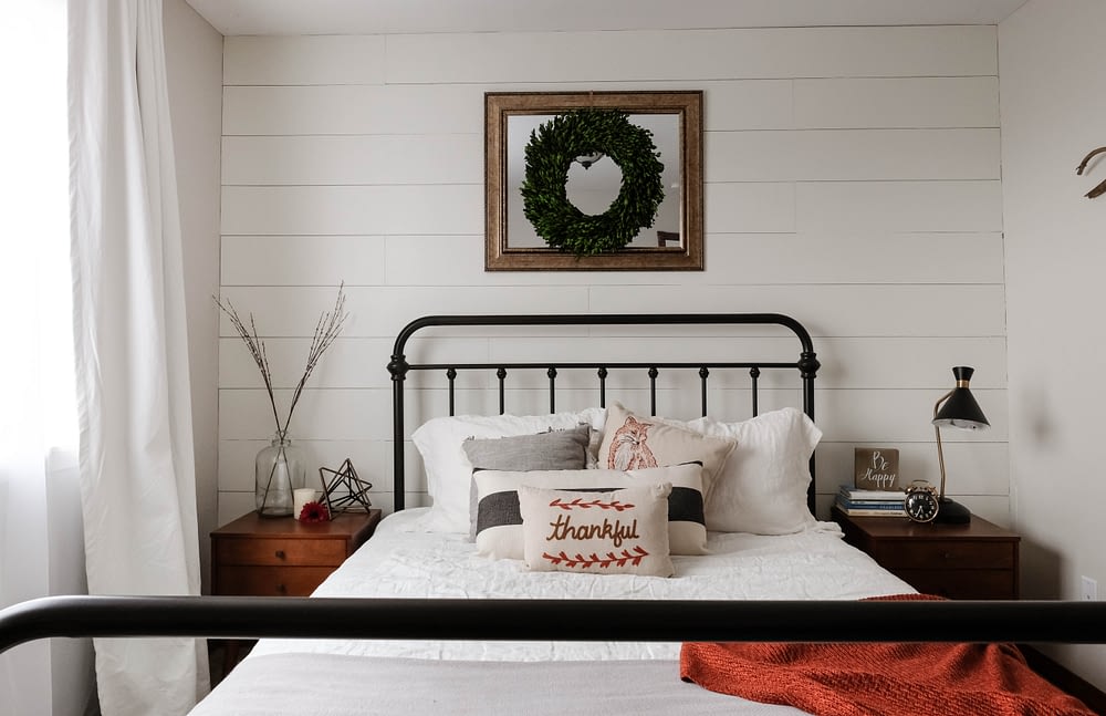 farmhouse bedroom with headboard against white shiplap accent wall