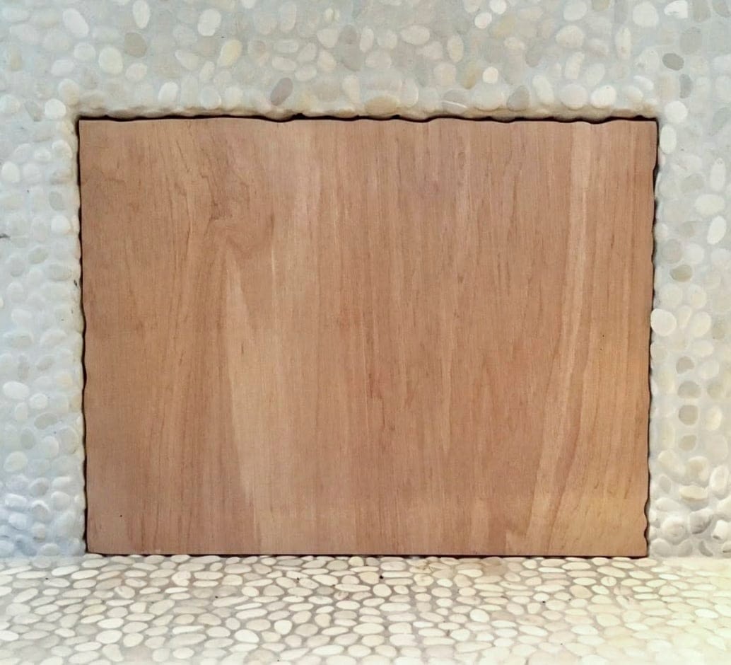 Square piece of plywood sitting as a fireplace insert to block draft