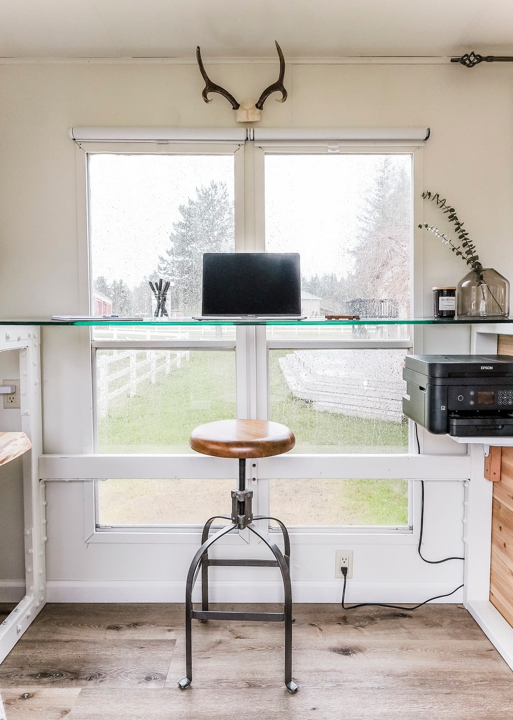 Standing desk with glass desk top in front of large windows