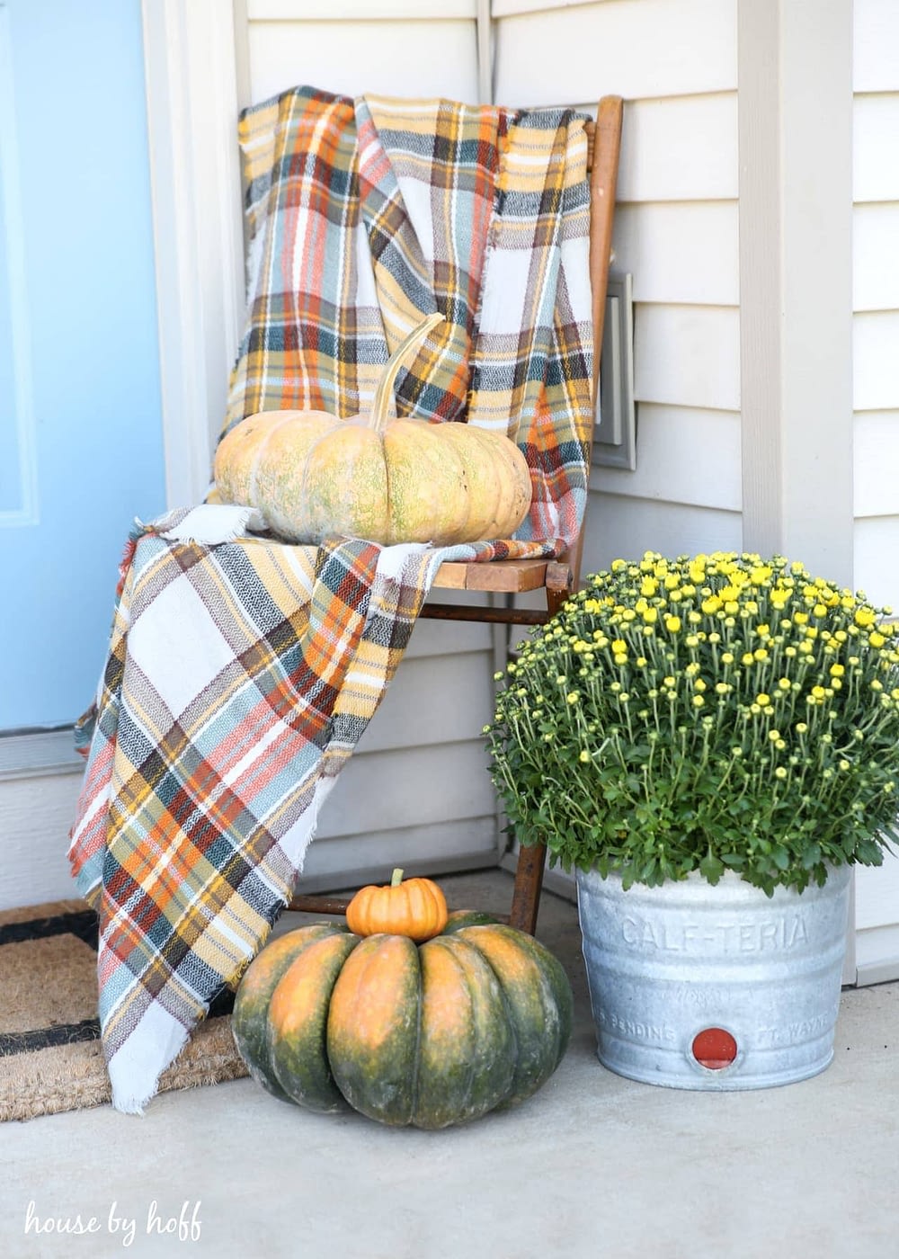 Fall front porch ideas using a plaid scarf draped over a chair with some pumpkins in a corner